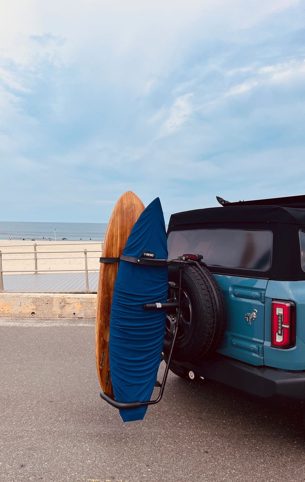 Turquoise SUV at the beach with two surfboards on RadRack